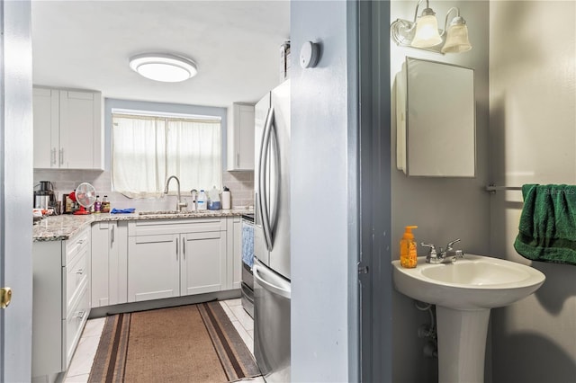 kitchen with white cabinetry, sink, light tile patterned floors, and tasteful backsplash