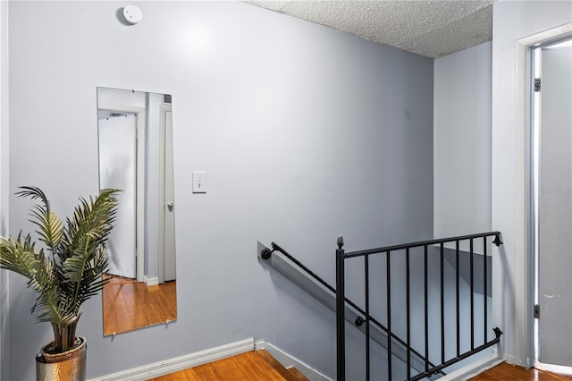 staircase with hardwood / wood-style flooring and a textured ceiling