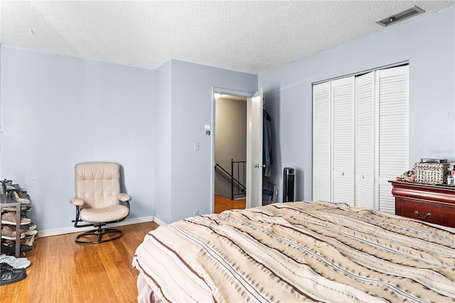 bedroom featuring hardwood / wood-style floors, a textured ceiling, and a closet