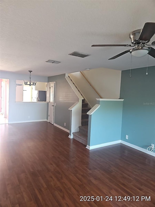 unfurnished living room featuring dark hardwood / wood-style floors, ceiling fan with notable chandelier, and a textured ceiling