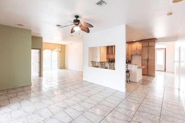 unfurnished living room featuring ceiling fan with notable chandelier