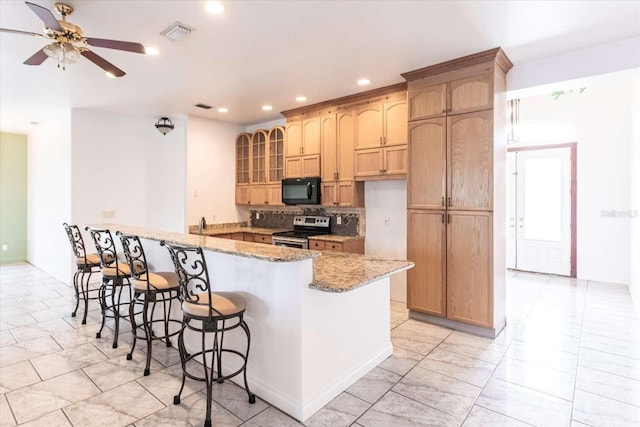 kitchen with a breakfast bar, ceiling fan, electric range, light stone counters, and kitchen peninsula