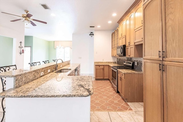 kitchen with stainless steel electric range oven, light stone countertops, a breakfast bar, and sink