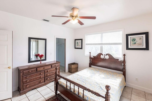 tiled bedroom with a walk in closet, ceiling fan, and a closet