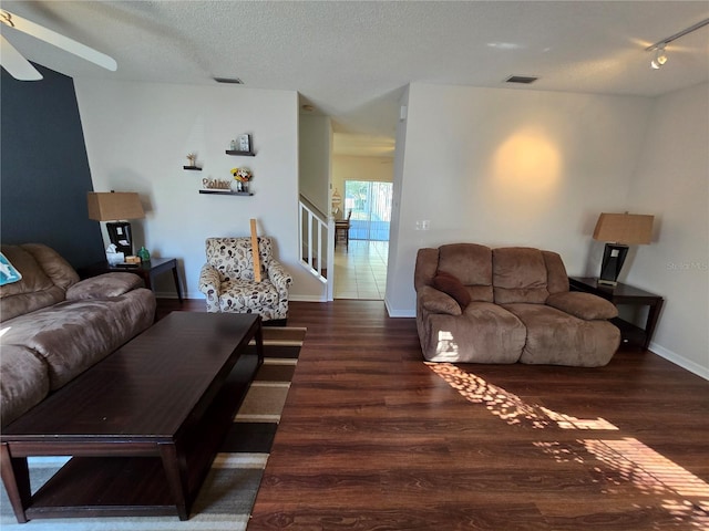 living room with ceiling fan, dark hardwood / wood-style floors, and a textured ceiling