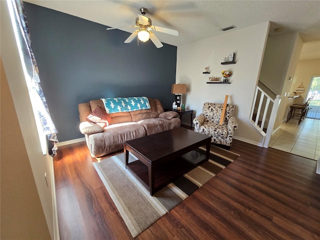 living room with dark hardwood / wood-style flooring, a textured ceiling, and ceiling fan