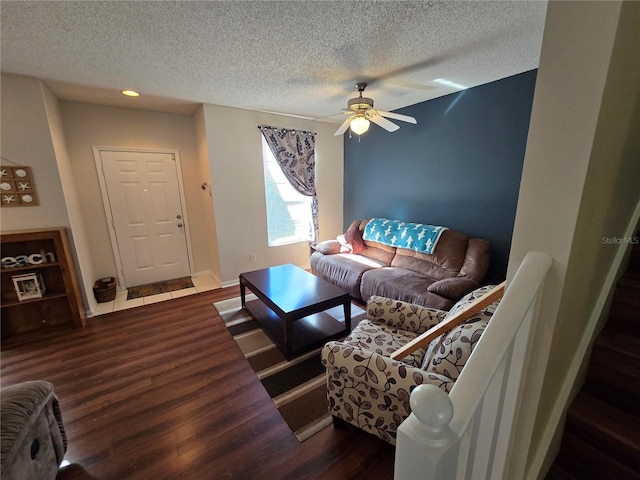 living room featuring ceiling fan, dark hardwood / wood-style floors, and a textured ceiling