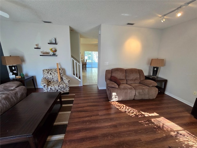 living room featuring rail lighting, dark hardwood / wood-style floors, and a textured ceiling