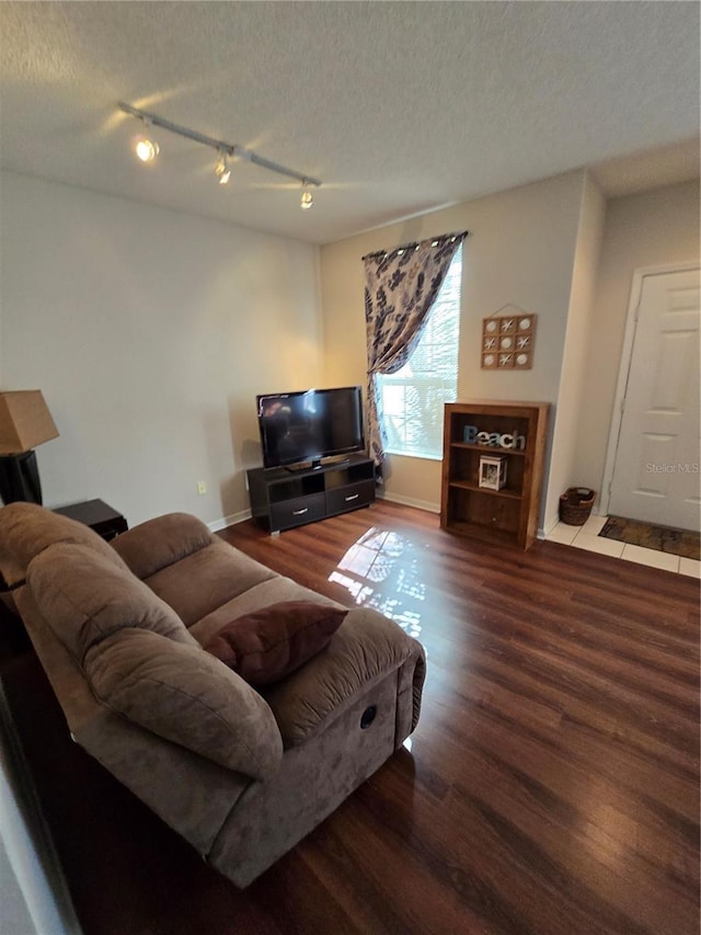 living room with wood-type flooring, track lighting, and a textured ceiling