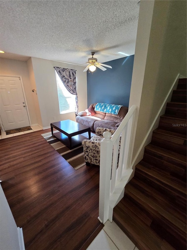 living room with ceiling fan, dark wood-type flooring, and a textured ceiling