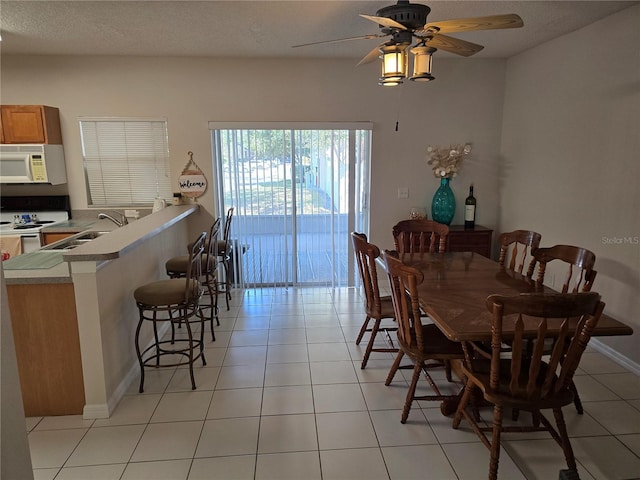 tiled dining space featuring ceiling fan, sink, and a textured ceiling