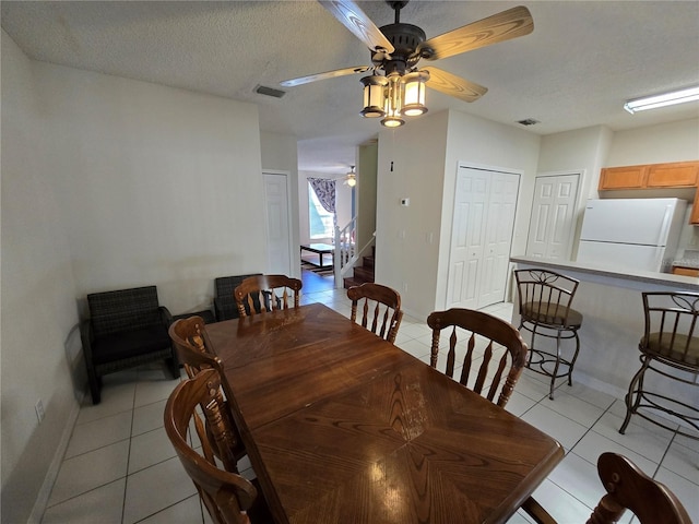 dining room featuring light tile patterned floors, a textured ceiling, and ceiling fan