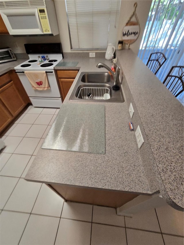 kitchen featuring light tile patterned flooring, sink, and white appliances