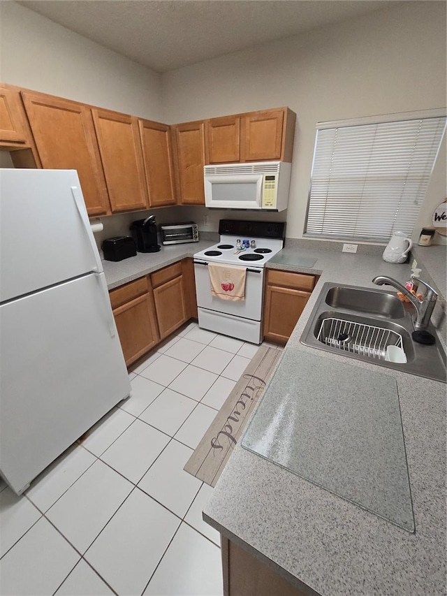 kitchen with white appliances, sink, and light tile patterned floors