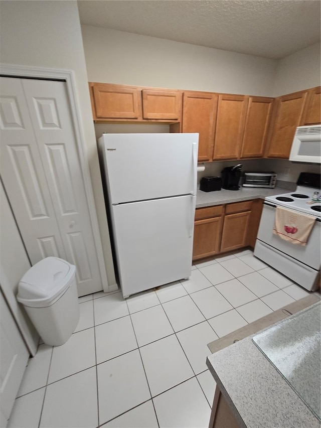 kitchen featuring light tile patterned floors, white appliances, and a textured ceiling