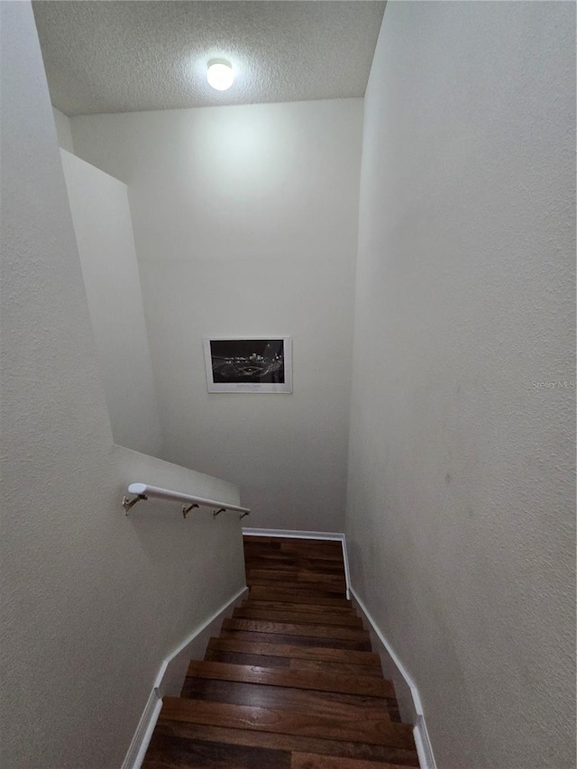 stairway featuring wood-type flooring and a textured ceiling