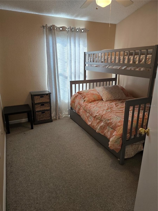 carpeted bedroom with ceiling fan and a textured ceiling