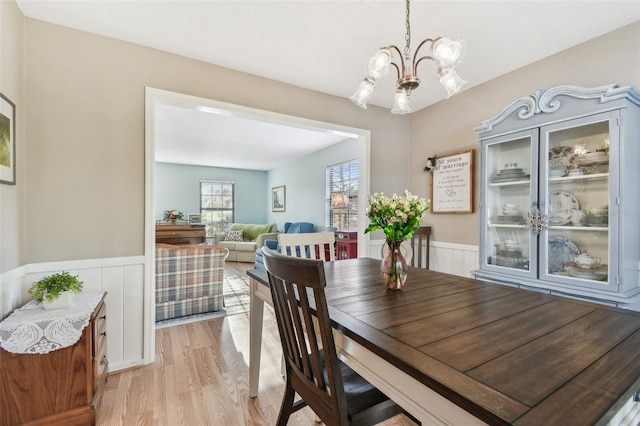 dining space with light hardwood / wood-style floors and a notable chandelier