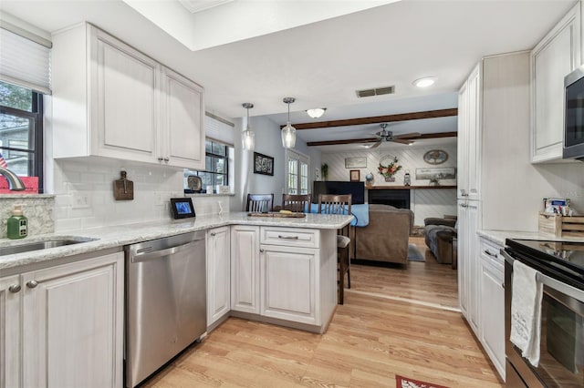 kitchen with white cabinetry, sink, kitchen peninsula, stainless steel appliances, and light wood-type flooring