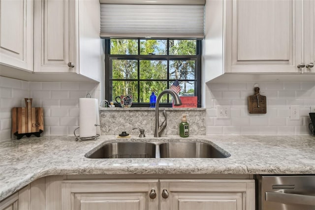 kitchen featuring tasteful backsplash, sink, stainless steel dishwasher, and light stone countertops