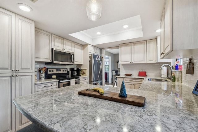 kitchen with stainless steel appliances, sink, kitchen peninsula, and a tray ceiling