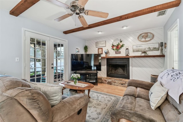 living room with ceiling fan, wooden walls, wood-type flooring, french doors, and beamed ceiling