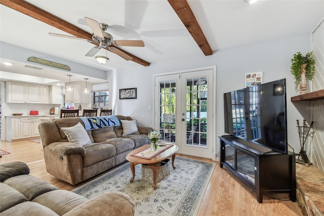 living room with beamed ceiling, ceiling fan, light wood-type flooring, and french doors