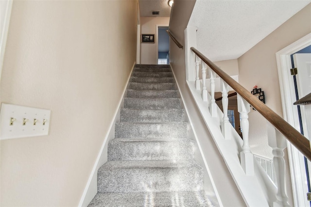 stairs featuring a textured ceiling