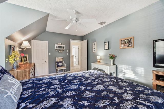 bedroom with ceiling fan, lofted ceiling, and a textured ceiling