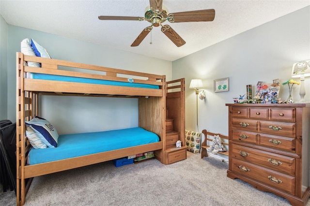 bedroom featuring ceiling fan, light carpet, and a textured ceiling