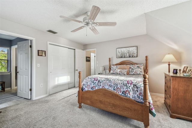 carpeted bedroom with ceiling fan, a closet, and a textured ceiling