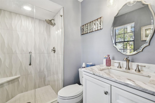 bathroom featuring vanity, a shower with shower door, and toilet