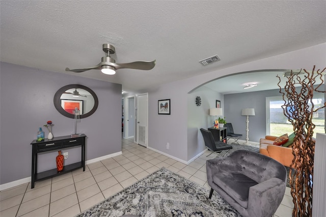 living room with ceiling fan, a textured ceiling, and light tile patterned flooring