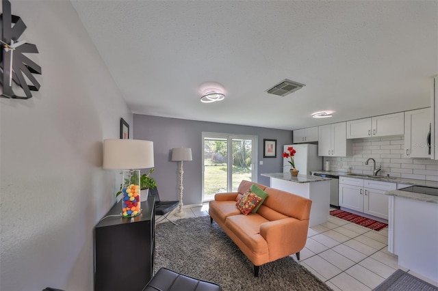 living room with sink, a textured ceiling, and light tile patterned floors