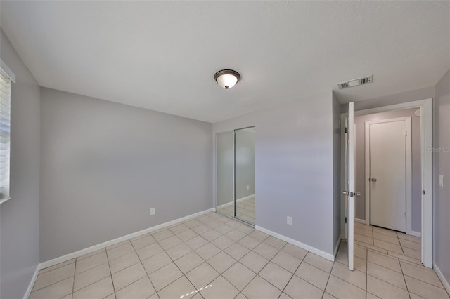 unfurnished bedroom with light tile patterned flooring and a closet