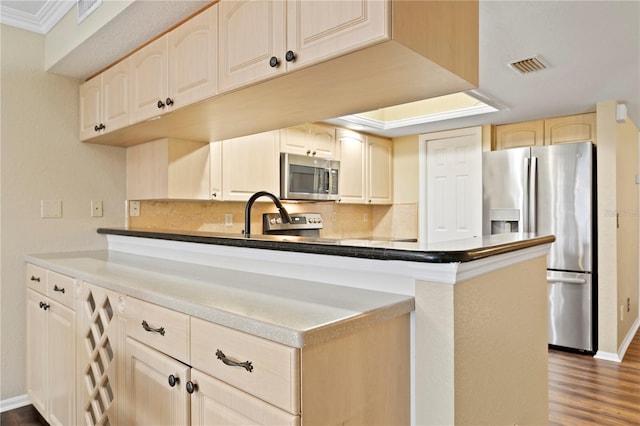 kitchen featuring stainless steel appliances, dark hardwood / wood-style flooring, kitchen peninsula, and decorative backsplash