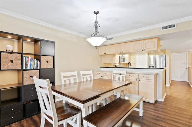 dining area with ornamental molding, dark hardwood / wood-style flooring, and sink