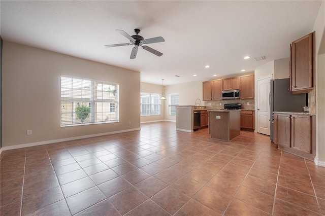 kitchen featuring stove, a center island, tile patterned floors, and ceiling fan