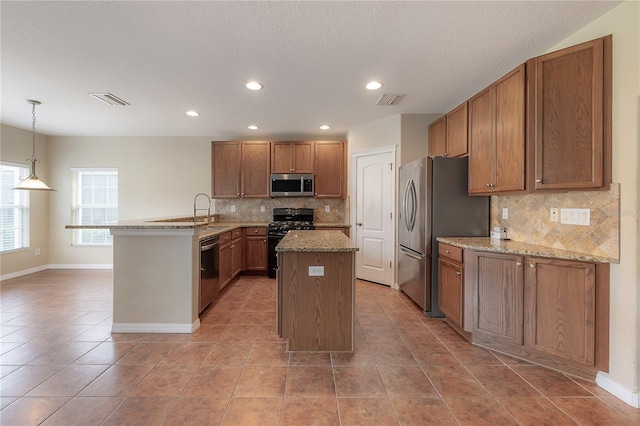 kitchen with sink, hanging light fixtures, an island with sink, stainless steel appliances, and decorative backsplash