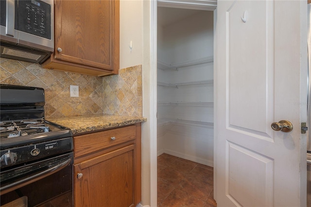 kitchen with decorative backsplash, light stone countertops, and black gas stove