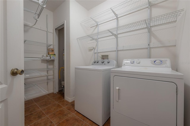 clothes washing area with dark tile patterned floors and washing machine and dryer