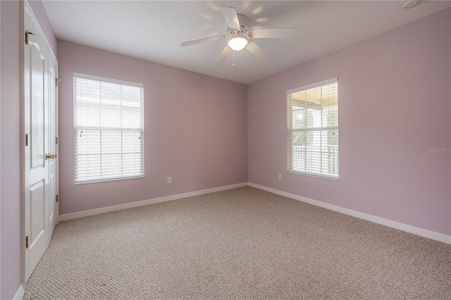 empty room with ceiling fan, light carpet, and a wealth of natural light