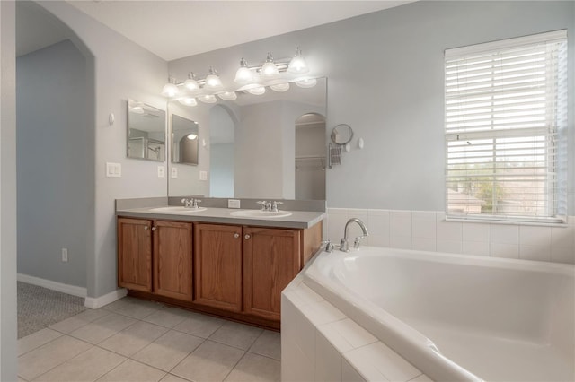 bathroom featuring vanity, a relaxing tiled tub, and tile patterned floors