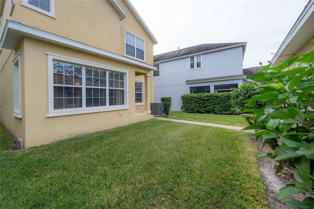 rear view of property featuring a yard and central AC unit