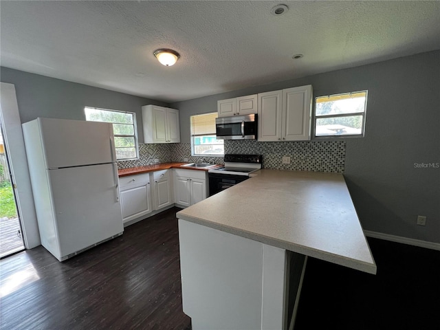 kitchen with white cabinetry, dark hardwood / wood-style floors, range with electric stovetop, kitchen peninsula, and white fridge