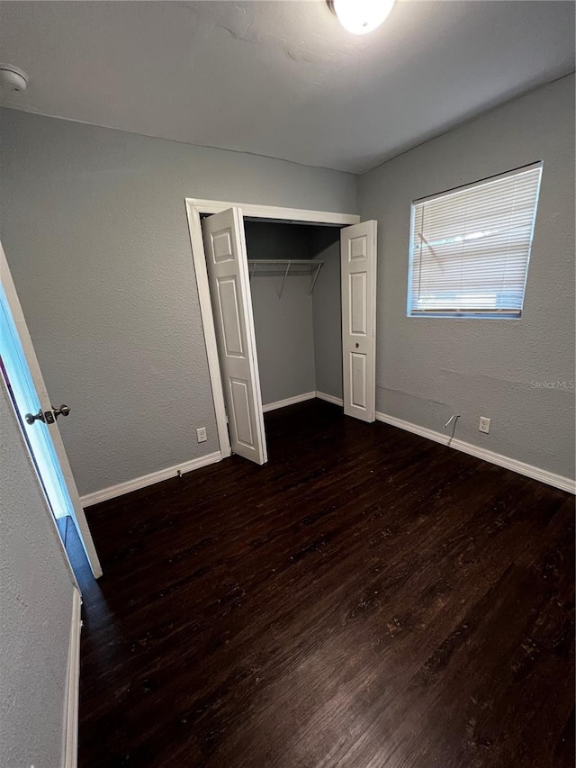 unfurnished bedroom with dark hardwood / wood-style flooring and a closet