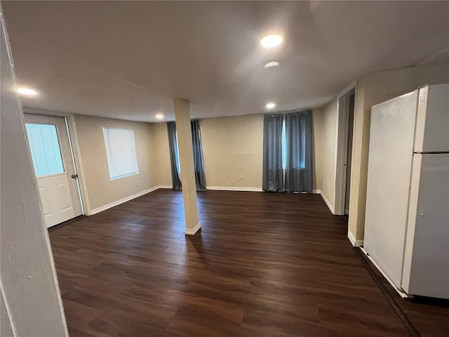 basement with white refrigerator and dark wood-type flooring