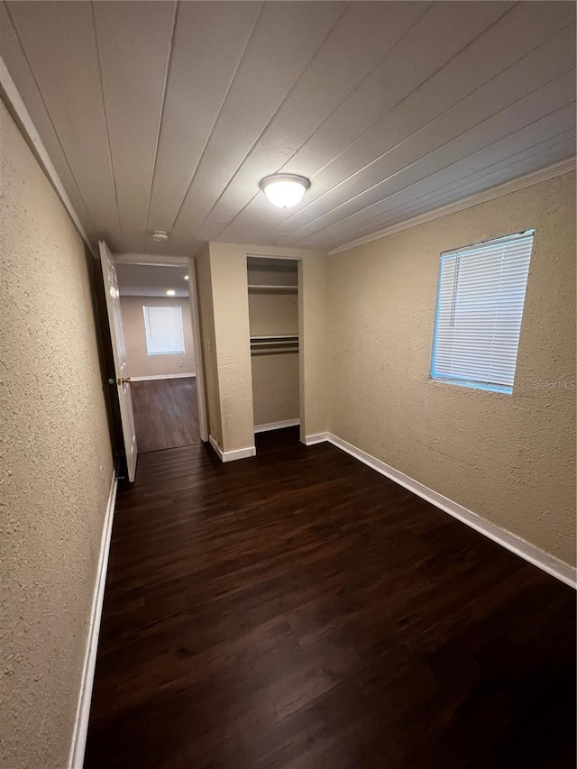 unfurnished bedroom featuring crown molding, dark hardwood / wood-style floors, and a closet