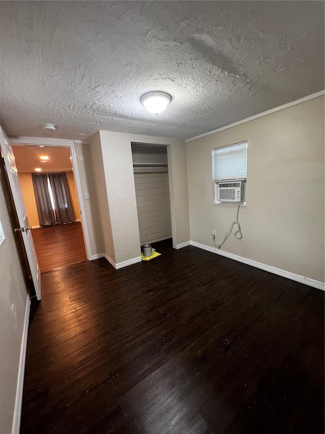 unfurnished bedroom with dark wood-type flooring, cooling unit, a textured ceiling, and a closet