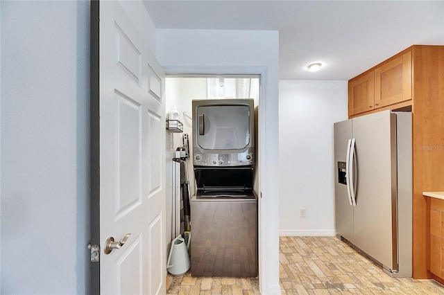 interior space featuring stacked washing maching and dryer and stainless steel fridge